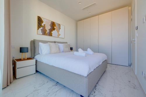 a white bedroom with a large bed and a night stand at Mercury Tower Apartments in St Julian's