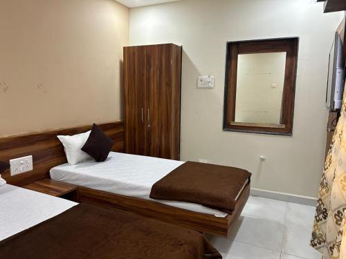 a hotel room with two beds and a mirror at Hotel Samruddhi Residency in Jamnagar