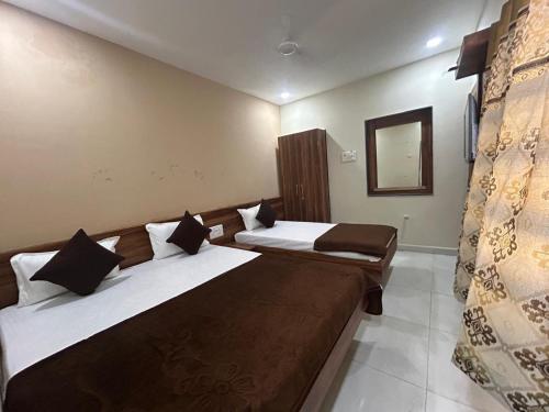 a hotel room with two beds and a mirror at Hotel Samruddhi Residency in Jamnagar