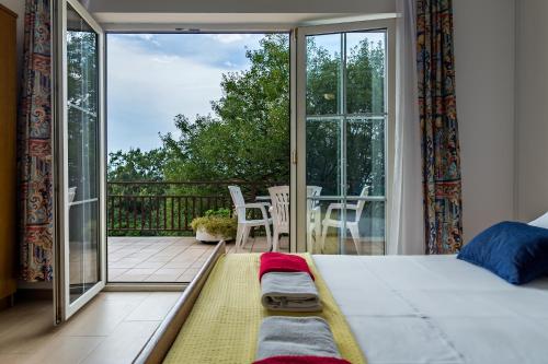 a bedroom with a bed and a balcony with a table at Apartments Claudia in Šmrika
