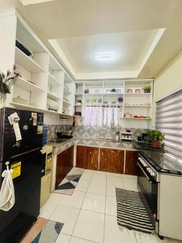 a kitchen with wooden cabinets and a black refrigerator at Elle's House in Dipolog