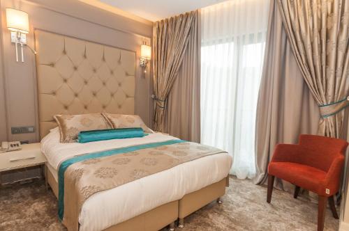 イスタンブールにあるPark Grazza Hotelのベッドと赤い椅子が備わるホテルルームです。