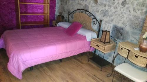 sypialnia z łóżkiem z różową kołdrą w obiekcie Apartamentos Anateresa w mieście Mogarraz