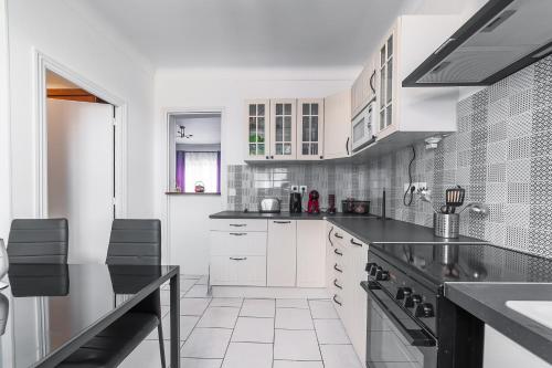 une cuisine avec des armoires blanches et des comptoirs noirs dans l'établissement Cosy Modern Apartment - 1 minute walk from train station, à Creil