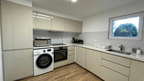 a kitchen with a washing machine and a sink at Appartement spacieux proche de Morges et Lausanne in Aclens