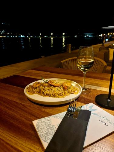 a plate of pasta on a table with a glass of wine at Aeolis Hotel in Samos