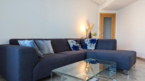 カーラ・デ・フィネストラットにあるVILA PARK Rooftop Apartmentのリビングルーム(ガラステーブル付)の青いソファ