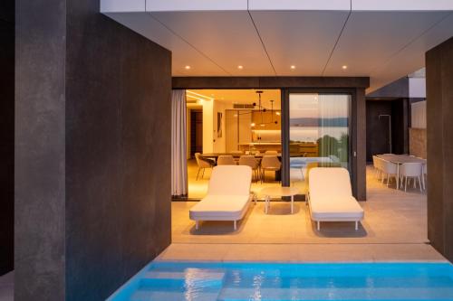 a house with a swimming pool and white chairs at Villa Brela-Rogac 1 in Baška Voda