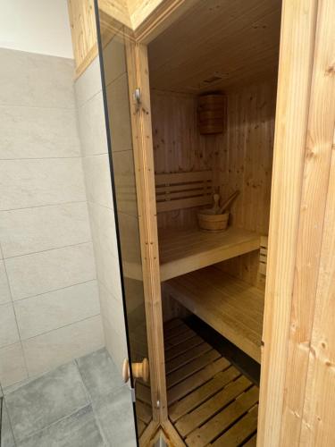 a wooden sauna with a glass door in a room at Jaśminowy Sad in Mikołajki