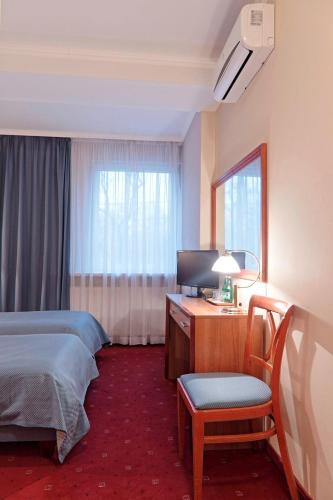 a hotel room with a bed and a desk and a television at Hotel Gold in Poznań