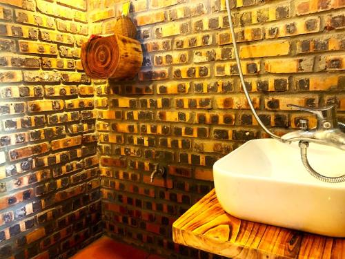 a bathroom with a sink and a brick wall at Pu Luong Cuisine Garden Homestay in Làng Bang