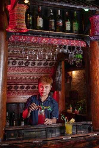 a young man standing behind a bar with a drink at Gateway Inn Puluong in Pu Luong