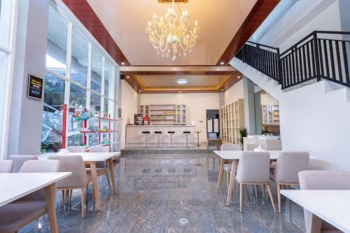 a dining room with tables and chairs and a chandelier at Grand Valonia Hotel Cafe & Park Jember in Jember