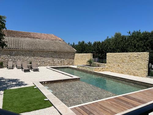a backyard with a swimming pool and chairs and a building at Le Mas d'Archas Montélimar Sud in Allan