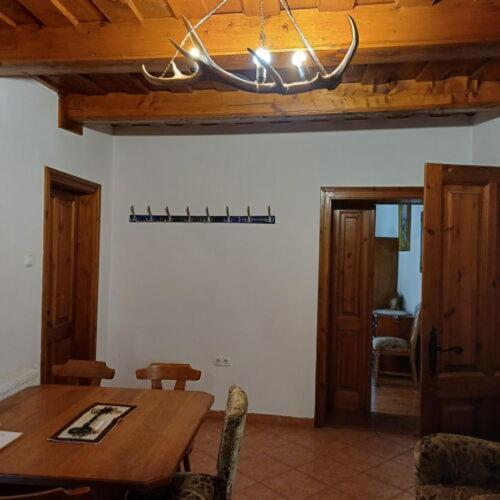 a dining room with a wooden table and a chandelier at Zanati Apartmannház in Nagykapornak