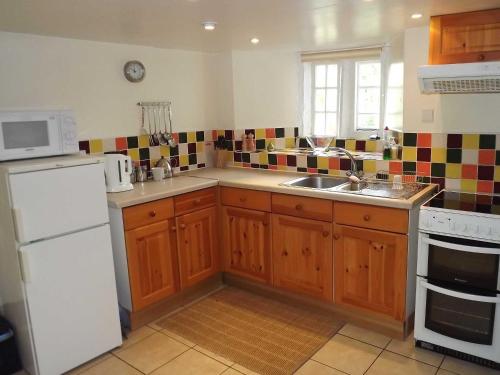 a kitchen with a white refrigerator and a sink at Skellgill House in Askrigg