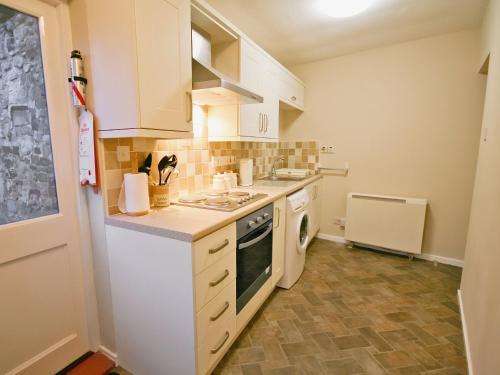 a small kitchen with white cabinets and a stove at The Old Reading Room in Bamburgh