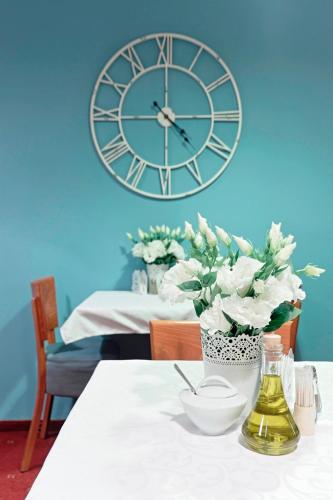 a large clock on the wall above a table with flowers at Hotel Gold in Poznań
