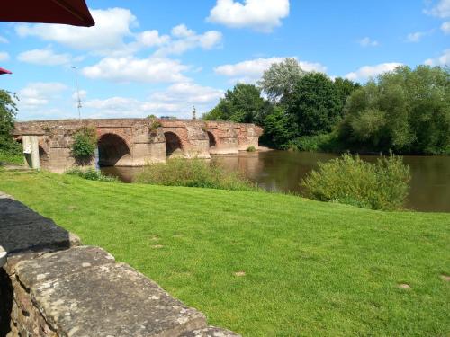 a bridge over a river with a grass field at The Bungalow, Forest of Dean in Coleford