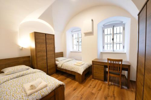 Un dormitorio con dos camas y un escritorio y dos ventanas. en Apartments Metro 7, en Liubliana