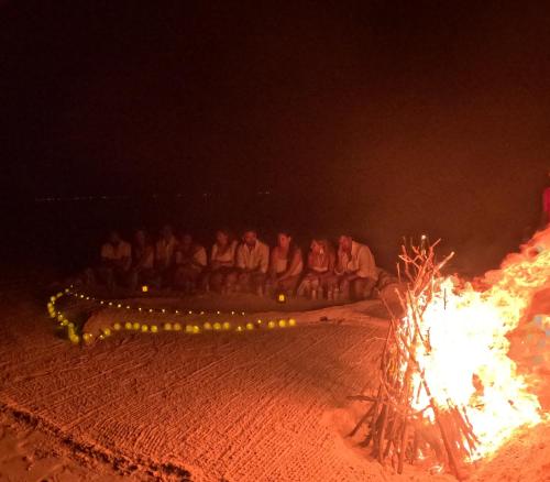 a group of people standing around a fire in the sand at Aqua Sunset in Gulhi
