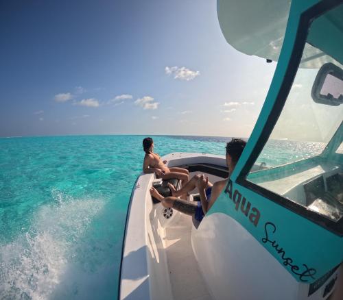 two men sitting on the back of a boat in the ocean at Aqua Sunset in Gulhi