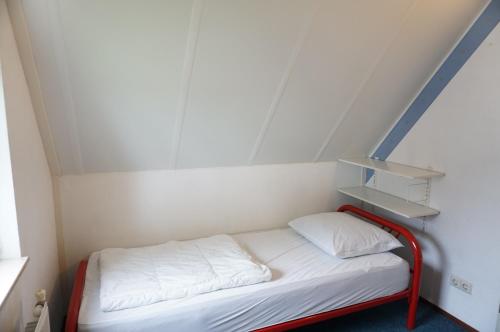 a small room with a bed with white sheets and shelves at Kustverhuur, Park Schoneveld Stern 188 in Breskens