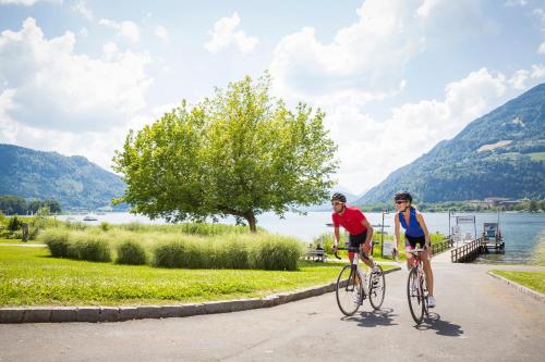 two people riding bikes on a path next to a lake at Ferienhaus Ossiacher See in Stiegl
