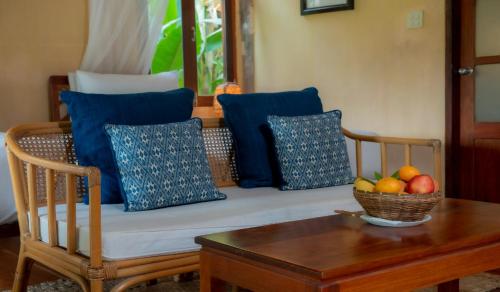 琅勃拉邦梦中精品度假村的沙发上放着蓝色靠枕，桌子上放着一碗水果。