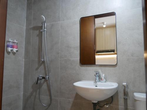 a bathroom with a sink and a shower with a mirror at Meisterstadt Pollux Habibie in Batam Center