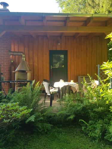 a wooden cabin with a table and a grill at Waldbadhäusel Naturbad-Bungalow in Neuwiese