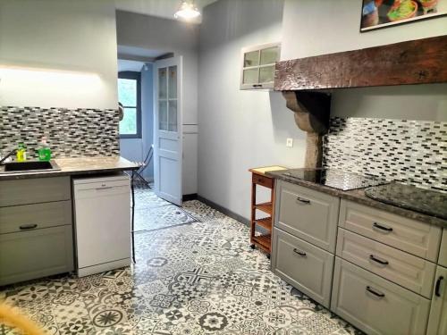 une cuisine avec des armoires blanches et un sol carrelé dans l'établissement La maison aux ardoises, à Oloron-Sainte-Marie