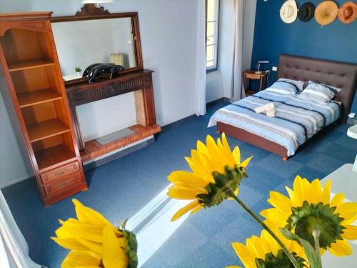 - une chambre avec un lit et une table ornée de fleurs jaunes dans l'établissement La maison aux ardoises, à Oloron-Sainte-Marie