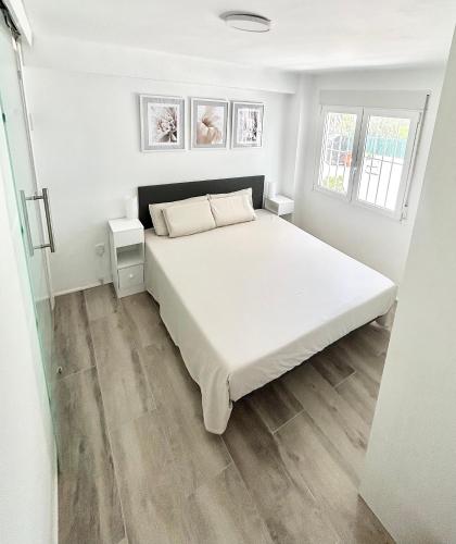 a bedroom with a white bed and two windows at Chalet con piscina privada en Alcocebre in Alcossebre