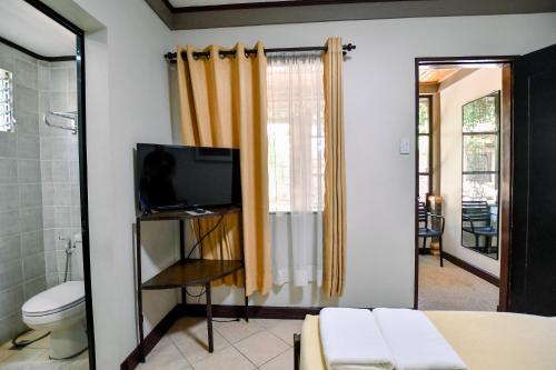 a bathroom with a toilet and a television in a room at Casa Basilisa Hotel & Resort in Guinobatan