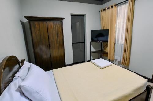 a bedroom with a bed and a cabinet and a television at Casa Basilisa Hotel & Resort in Guinobatan