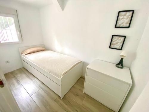 a small white bedroom with a bed and a night stand at Chalet con piscina privada en Alcocebre in Alcossebre