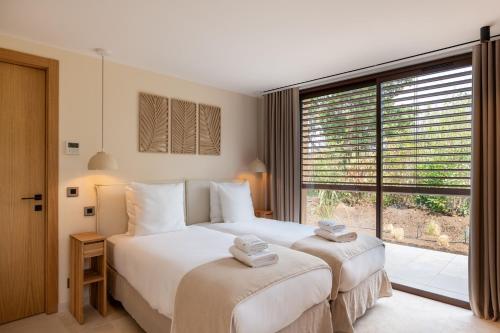 a bedroom with two beds and a large window at Les Maisons Du Sud in Saint-Tropez