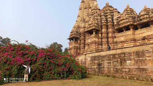 a man standing in front of a building with flowers at Abhiram Homestay in Khajurāho