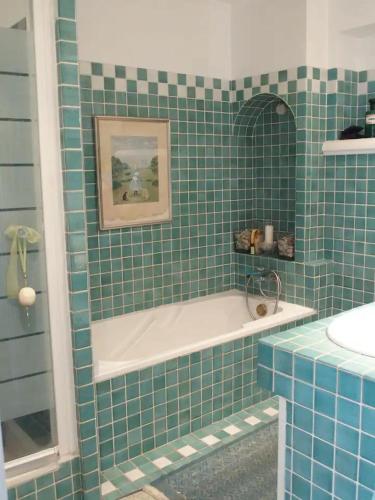La salle de bains est pourvue de carrelage vert, d'une baignoire et d'un lavabo. dans l'établissement Très jolie villa à Vence, à Vence