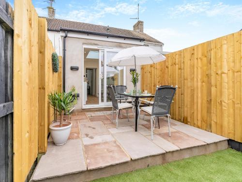 a patio with a table and chairs and an umbrella at Wick Cottage in Nottage