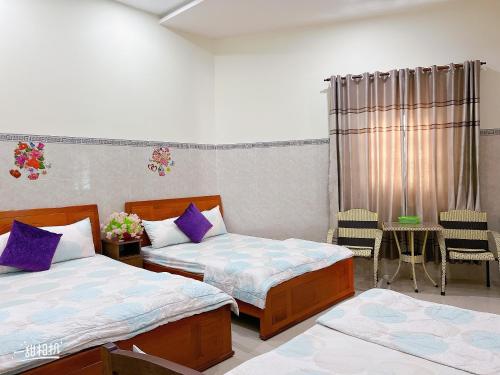 a bedroom with two beds and a table and chairs at Nhà nghỉ 72 in Long Hai