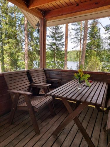 a wooden porch with a picnic table and chairs on it at Koivurannan Lomamökit Kataja in Mikkeli