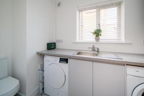 a bathroom with a sink and a washing machine at Mallard House in Yarmouth