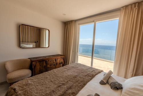 ein Schlafzimmer mit einem großen Fenster, einem Bett und einem Stuhl in der Unterkunft Villa Bianca in Callao Salvaje