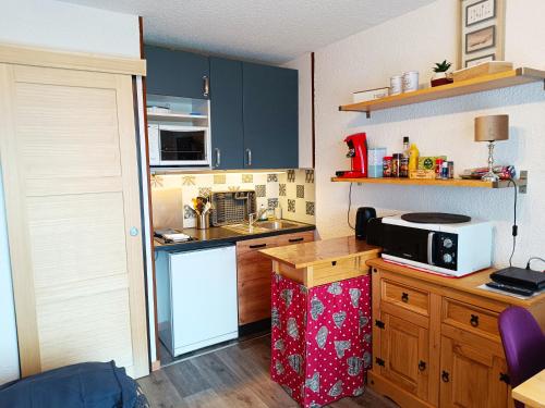 une cuisine avec des placards bleus et un four micro-ondes sur un comptoir dans l'établissement Les Hauts De Saint Gervais, à Saint-Gervais-les-Bains