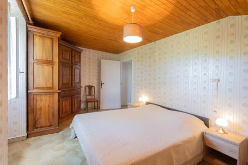 - une chambre avec un lit blanc et un plafond en bois dans l'établissement Nouveau ! Maison en pierre, Nature, à Joyeuse