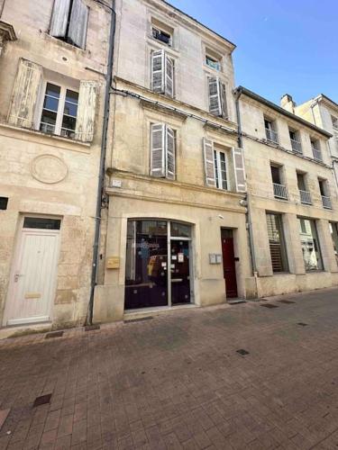 un vieux bâtiment avec une porte ouverte sur une rue dans l'établissement Les Arches, à Saintes
