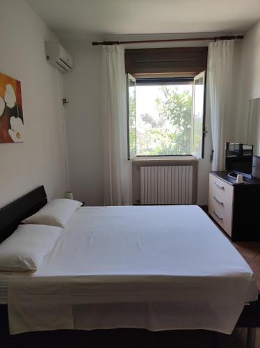 a bedroom with a large white bed and a window at Contrada Macchia B&B in Tricase