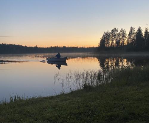 a man in a boat on a lake at sunset at Guesthouse Koli Freetime in Ahmovaara